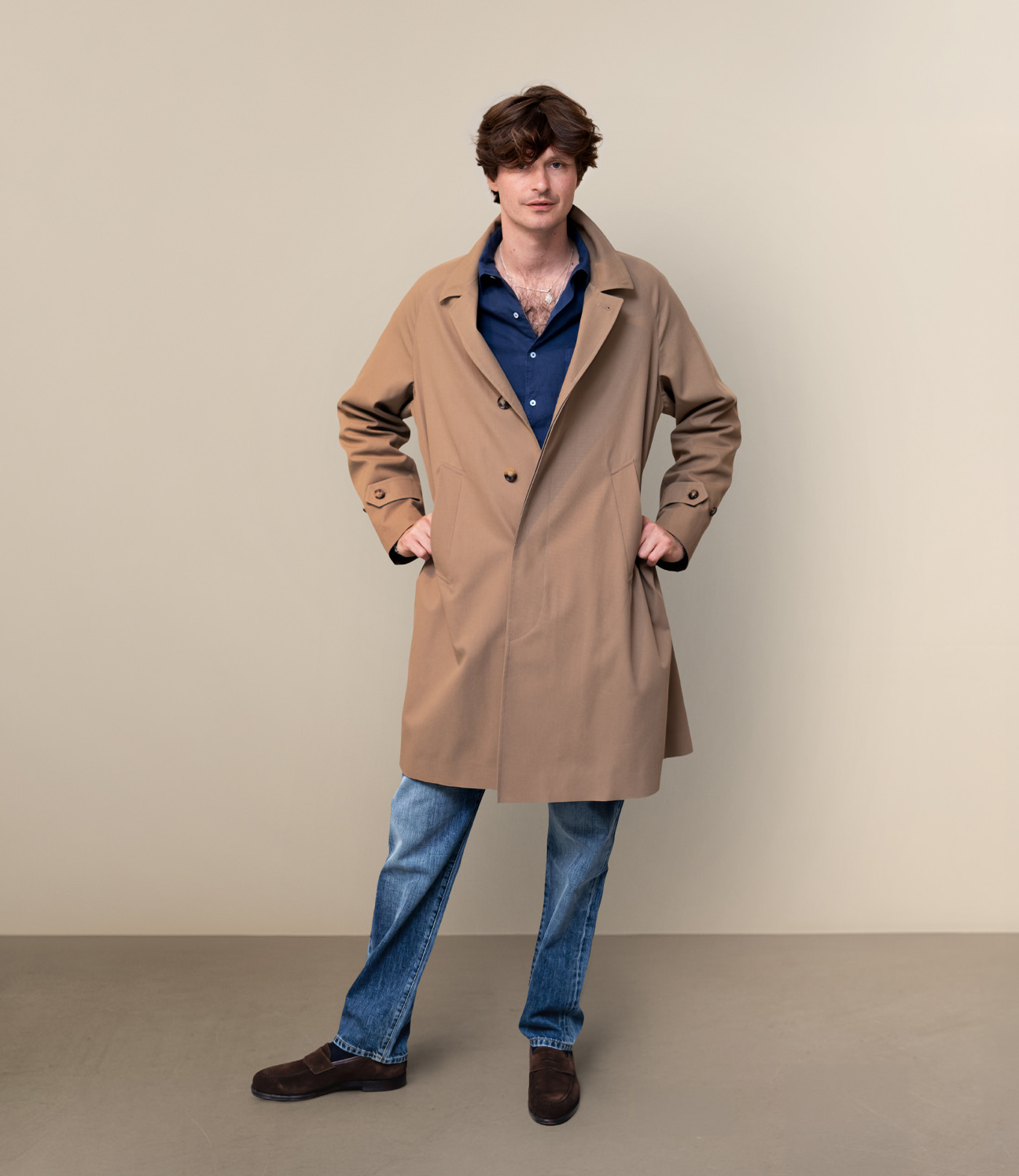 Man wearing a beige trench coat and navy shirt from Garodkin