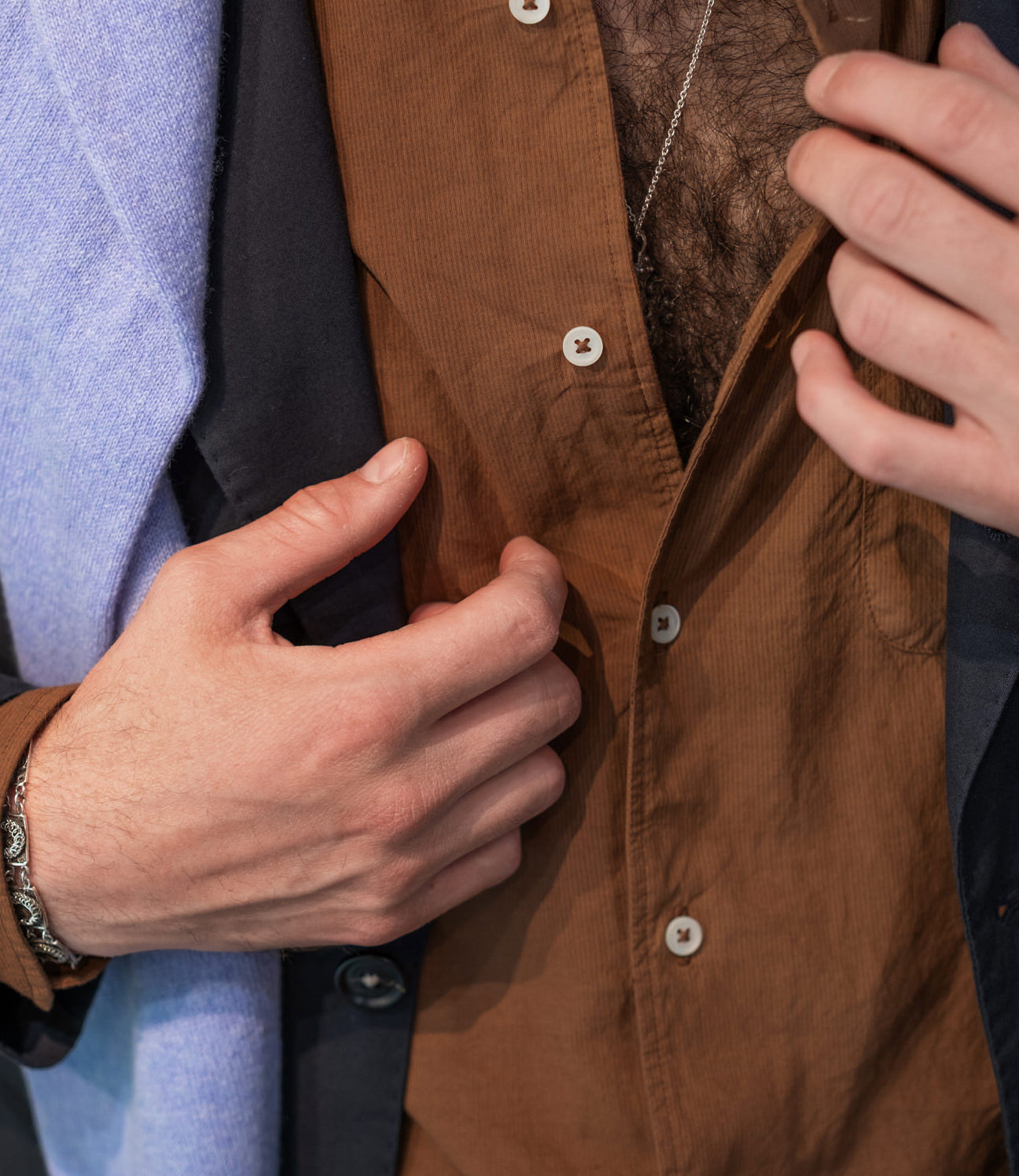 Hands buttoning a brown waistcoat from Garodkin